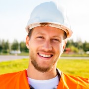 Smiling man with dark facial hair wearing a hard hat